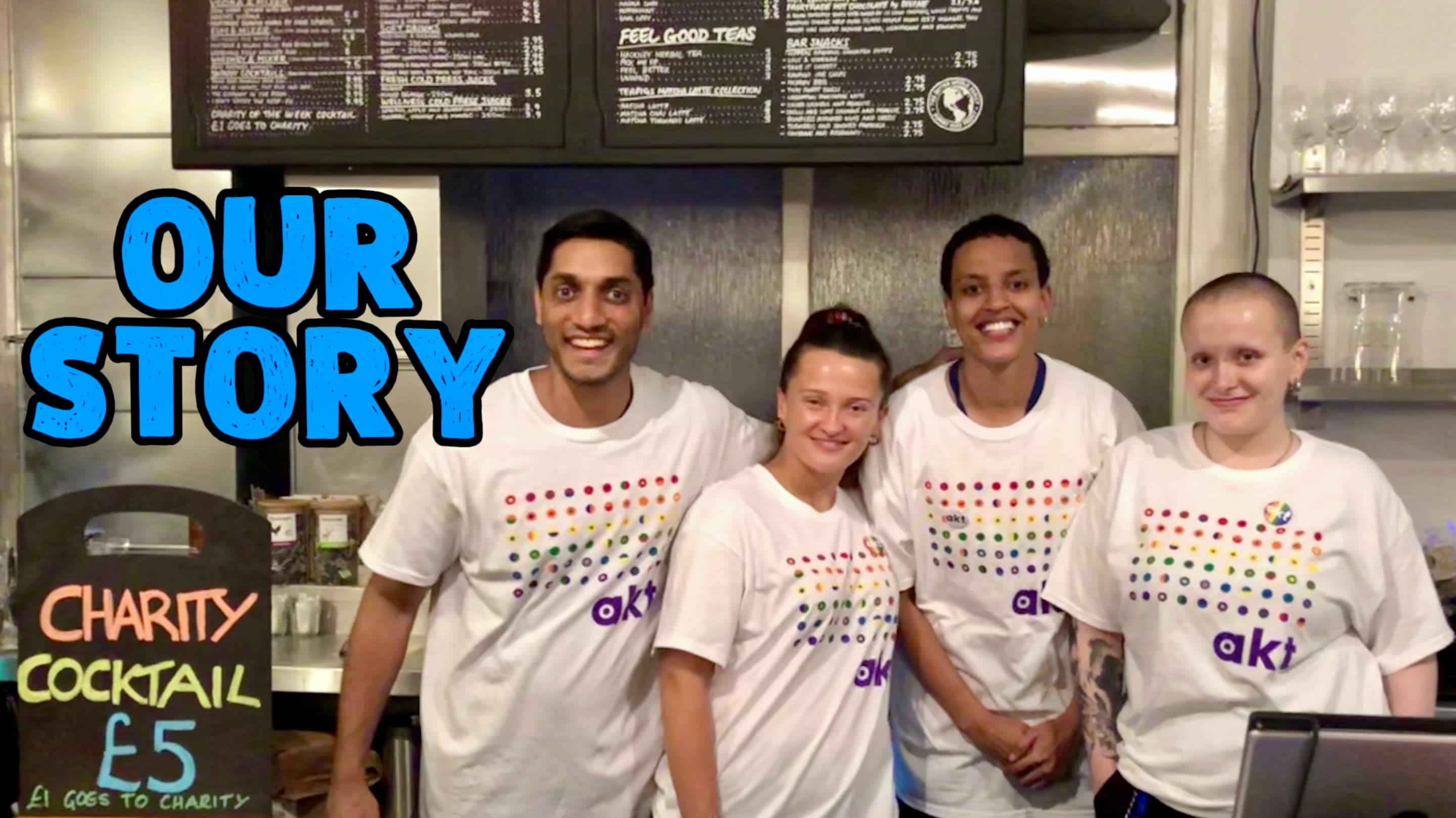 Video thumbnail titled Our Story — four smiling Green Vic team members in charity partner t-shirts behind the bar, beside a chalkboard reading Charity Cocktail five pounds, one pound goes to charity