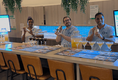 Three smiling bartenders preparing cocktails behind a premium mobile event bar