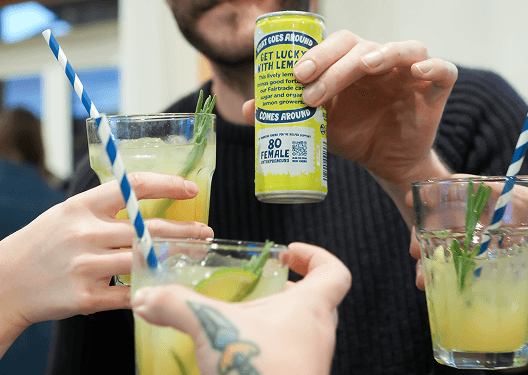 Guests toasting with fresh lemonade beside a Karma Drinks can