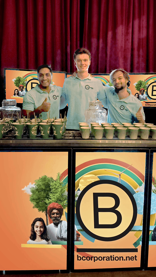 Three professional bartenders smiling and giving a thumbs up behind a digital mobile event bar displaying custom Certified B Corporation branding. The setup features eco friendly cups and is ready to deliver sustainable hospitality for a corporate event or brand activation.