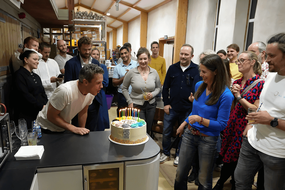 Guests cheer and clap while a man with his hands raised celebrates a woman cutting the Certified B Corporation birthday cake at the B Lab celebration