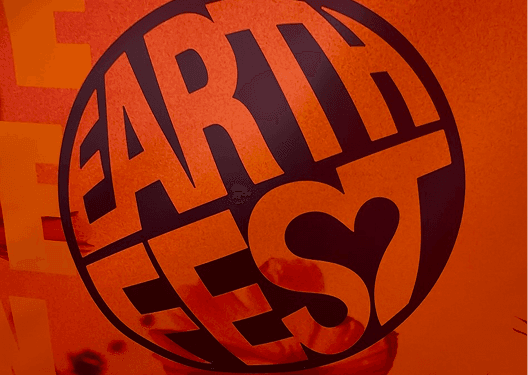 A close up graphic of the circular Earthfest festival logo on a bright orange background