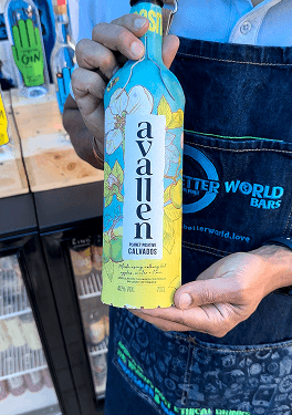A close up of a bartender holding a beautifully illustrated bottle of planet positive