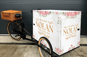 A compact drinks tricycle fully customised with a beautiful floral design and personalised wedding branding to welcome guests at a luxury reception