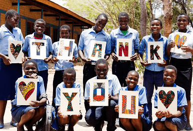 Beneficiaries holding 'THANK YOU' letters, representing measurable social impact