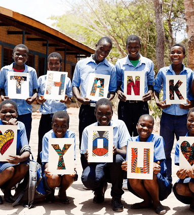 Schoolchildren in Africa holding up hand-painted letters spelling THANK YOU