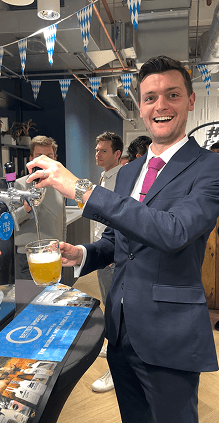 A smiling client in a suit pouring himself a beer at a BetterWorld event bar
