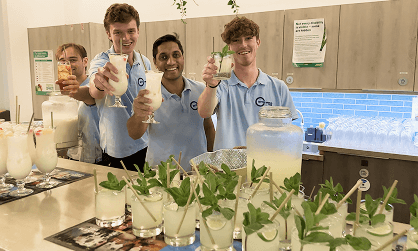 Our founder Randy Rampersad standing with three smiling team members giving thumbs up behind a sustainable event bar representing our mission of changing lives one shift at a time through ethical employment