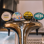 A close up of four different beer and cider tap handles at a bar representing how every drink purchased at our ethical pub donated to over fifty different charities