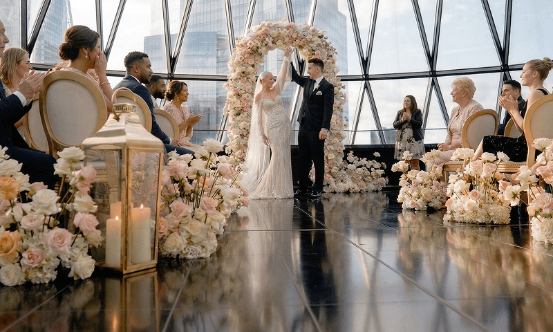 A newly married couple celebrating under a stunning floral archway during their ceremony at The Gherkin representing a glowing review for our seamless mobile bar hire and luxury digital wedding bar from Hannah and Phillip