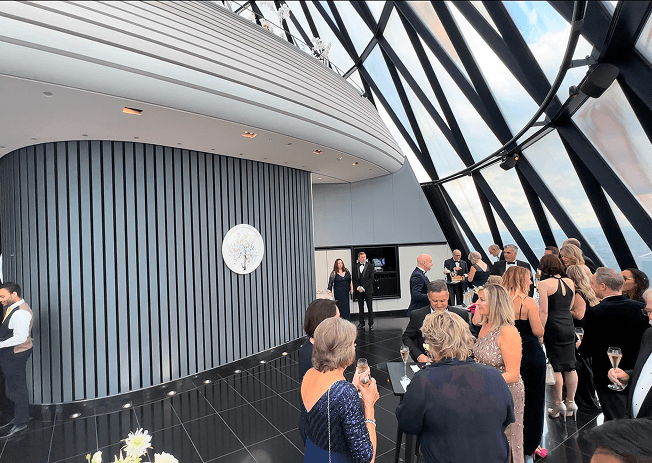 Wedding guests mingling in The Gherkin's reception hall beneath the building's diagonal glass ceiling