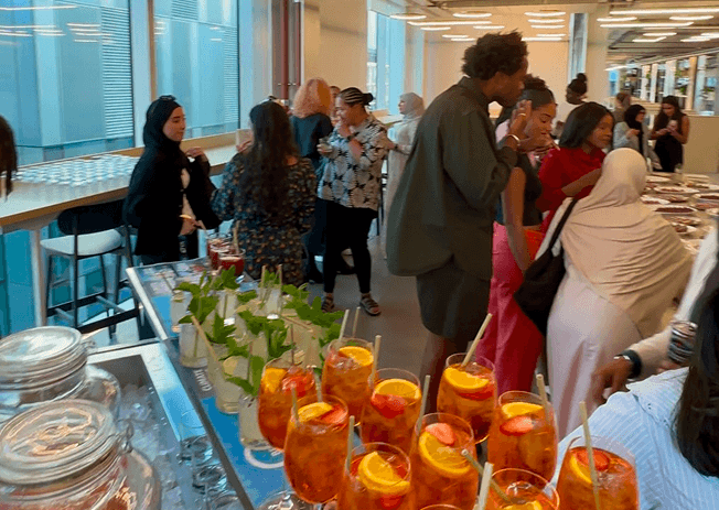 Guests mingling beside the event bar with Aperol spritzes and mojitos ready to serve in the foreground