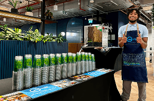 A professional bartender giving a thumbs up behind a mobile event bar set up in a modern office space ready for Thursday office drinks