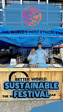 Two bartenders giving a thumbs up behind a sustainable wooden pop-up bar at Earthfest, showcasing Better World Bar Hire's eco-friendly festival event setup.