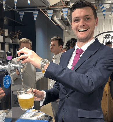 A smiling client in a suit pouring himself a beer at a BetterWorld event bar